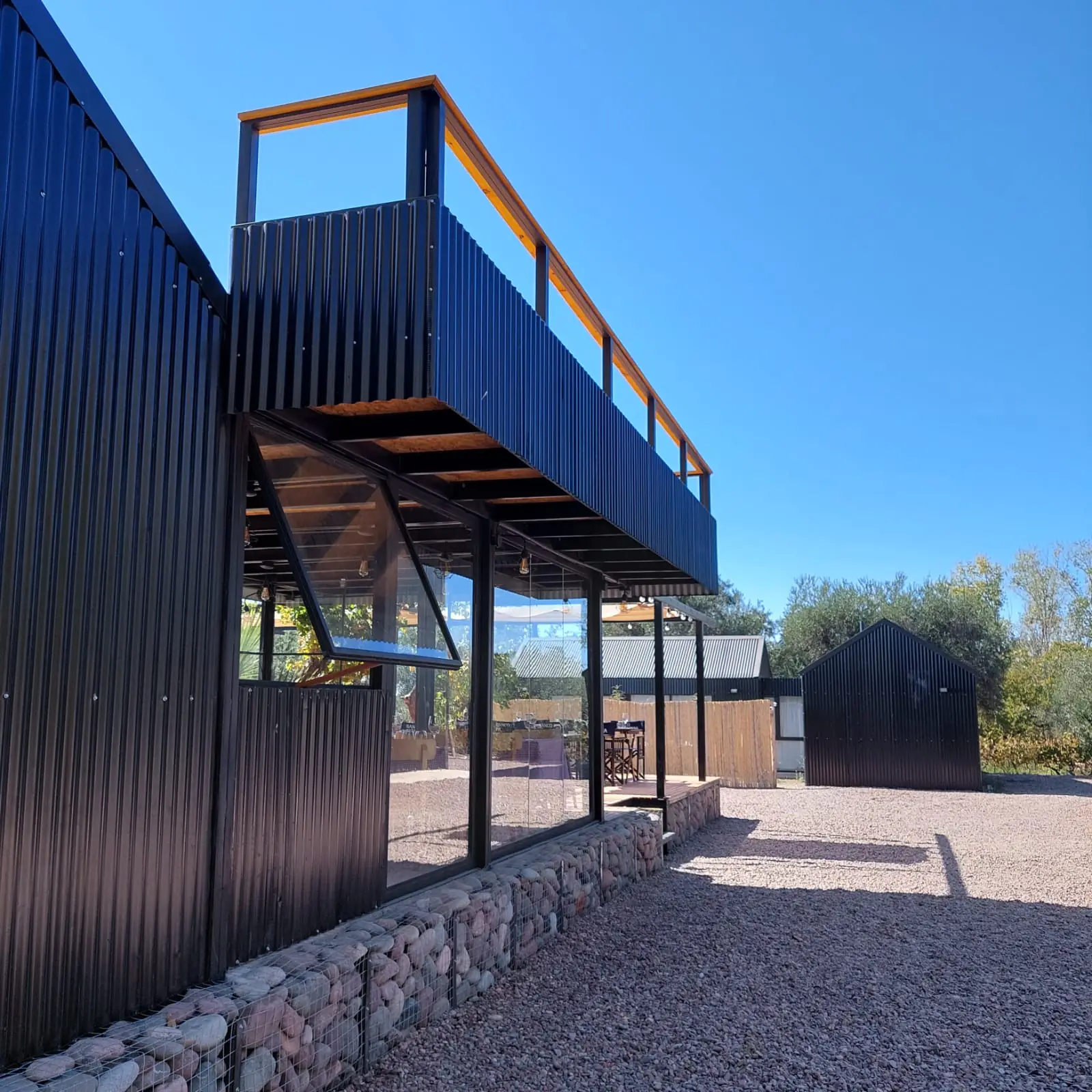 Volumen negro con terraza superior, escalera metálica y basamento de piedra