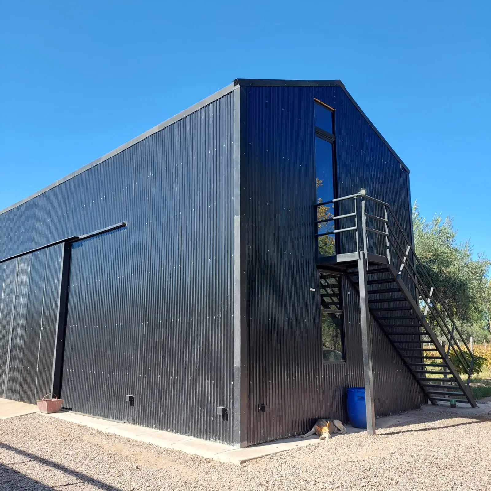 Fachada lateral ciega del volumen negro, con escalera exterior de acceso