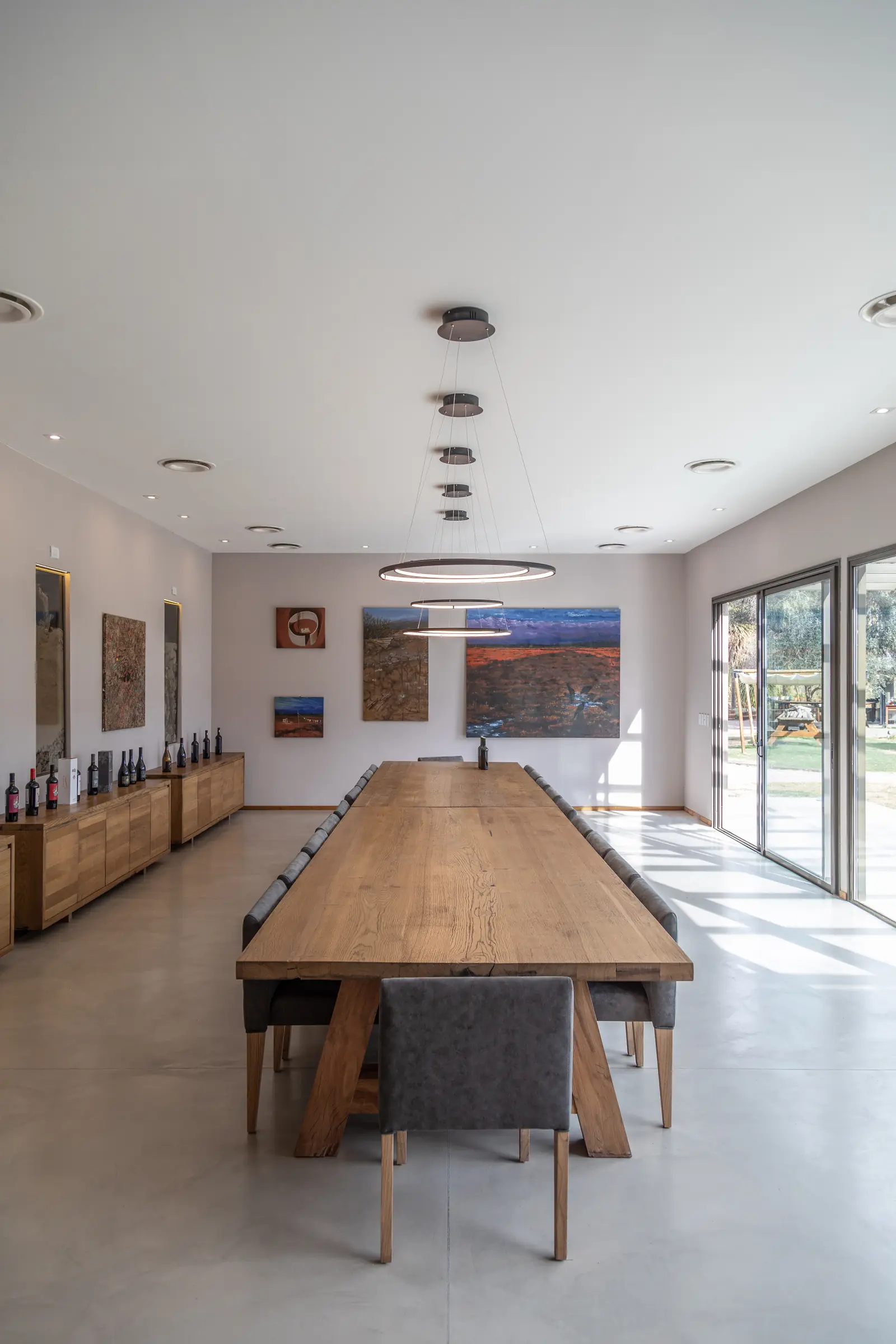 Interior de la sala hacia el ventanal, con mesa larga y lámparas circulares