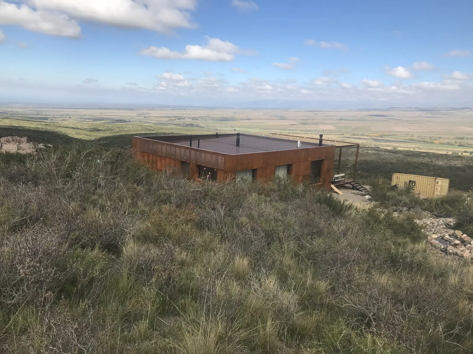 Vivienda revestida en acero corten sobre la loma con el valle al fondo