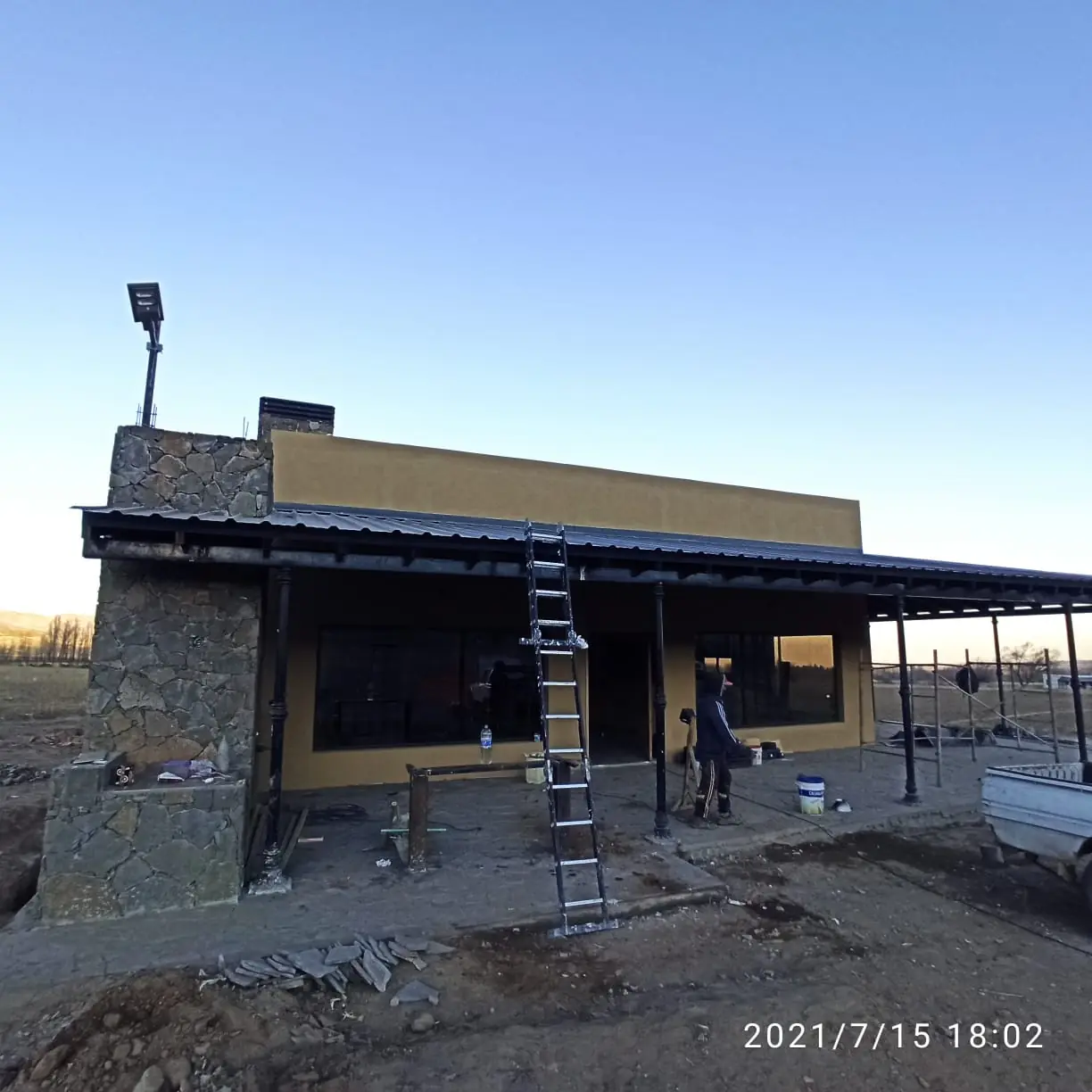 Vista general de la casa con chimenea de piedra y galería continua