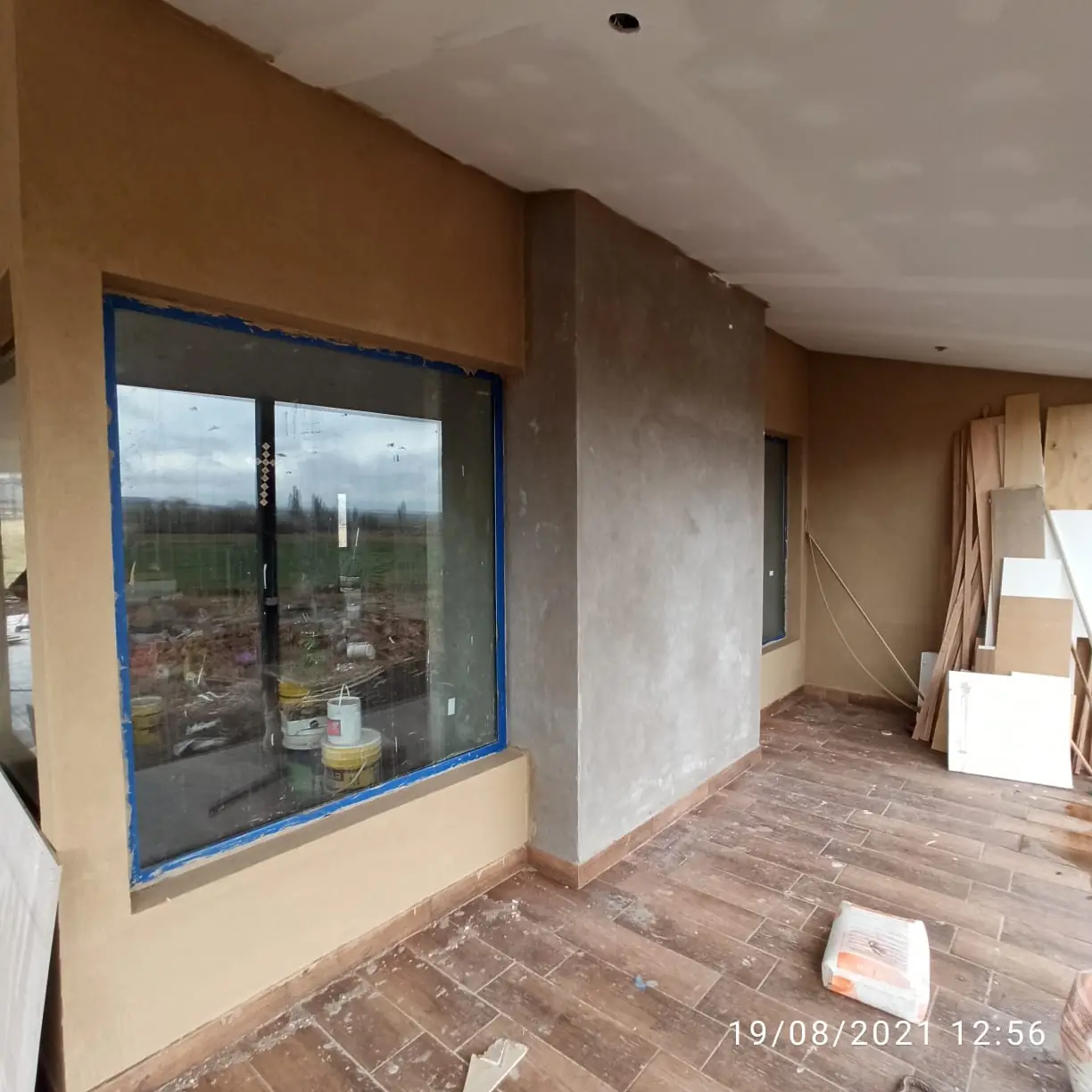 Ambiente interior con ventanal enmarcado en ocre y piso de madera