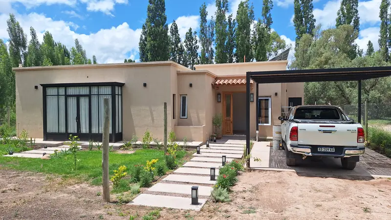 Frente de la casa con sendero de losetas, cantero y acceso cubierto
