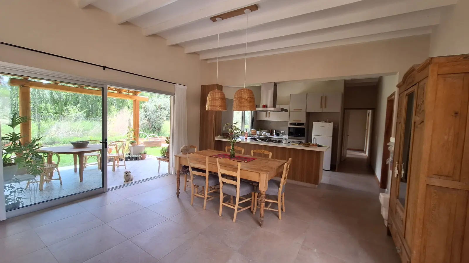 Comedor y cocina integrados con muebles de madera y salida al parque