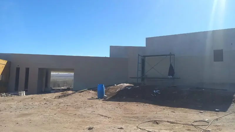 Fachada terminada de volúmenes revocados en gris con cubierta plana