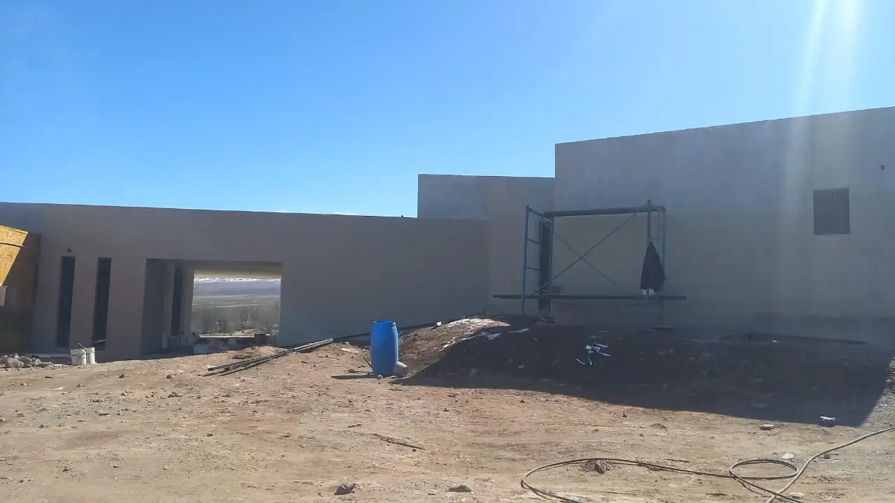 Fachada terminada de volúmenes revocados en gris con cubierta plana