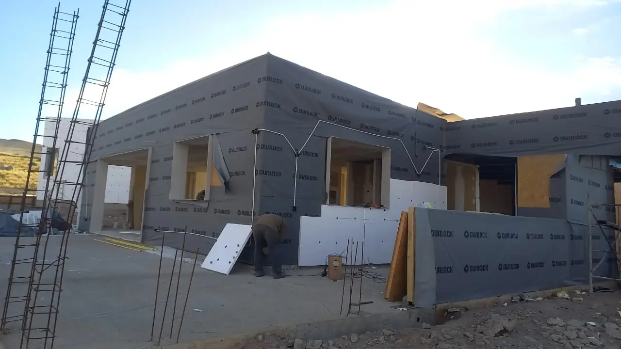 Frente de la vivienda con andamios y aberturas ya colocadas