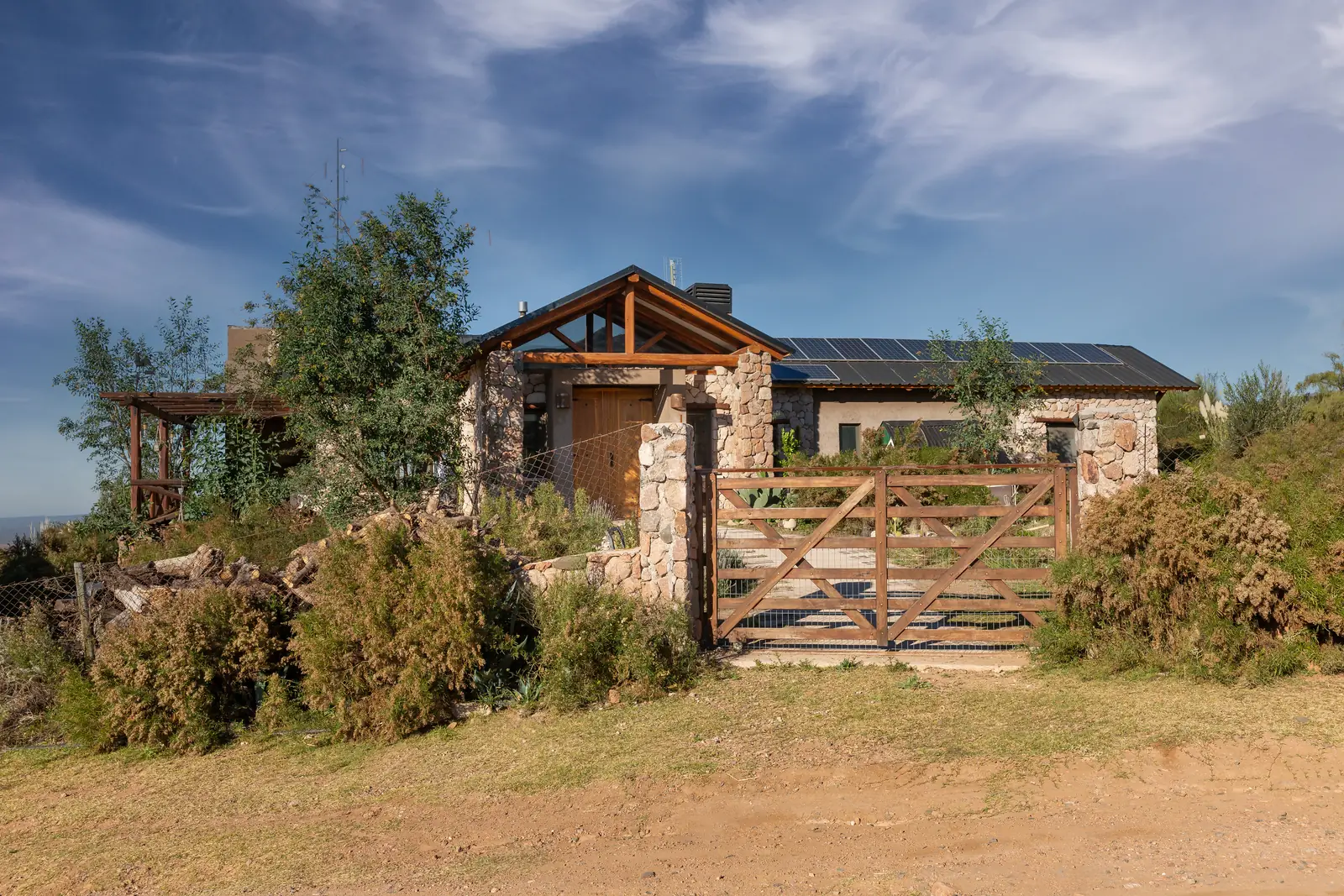 Casa completa detrás de la tranquera de madera, sobre el terreno en pendiente