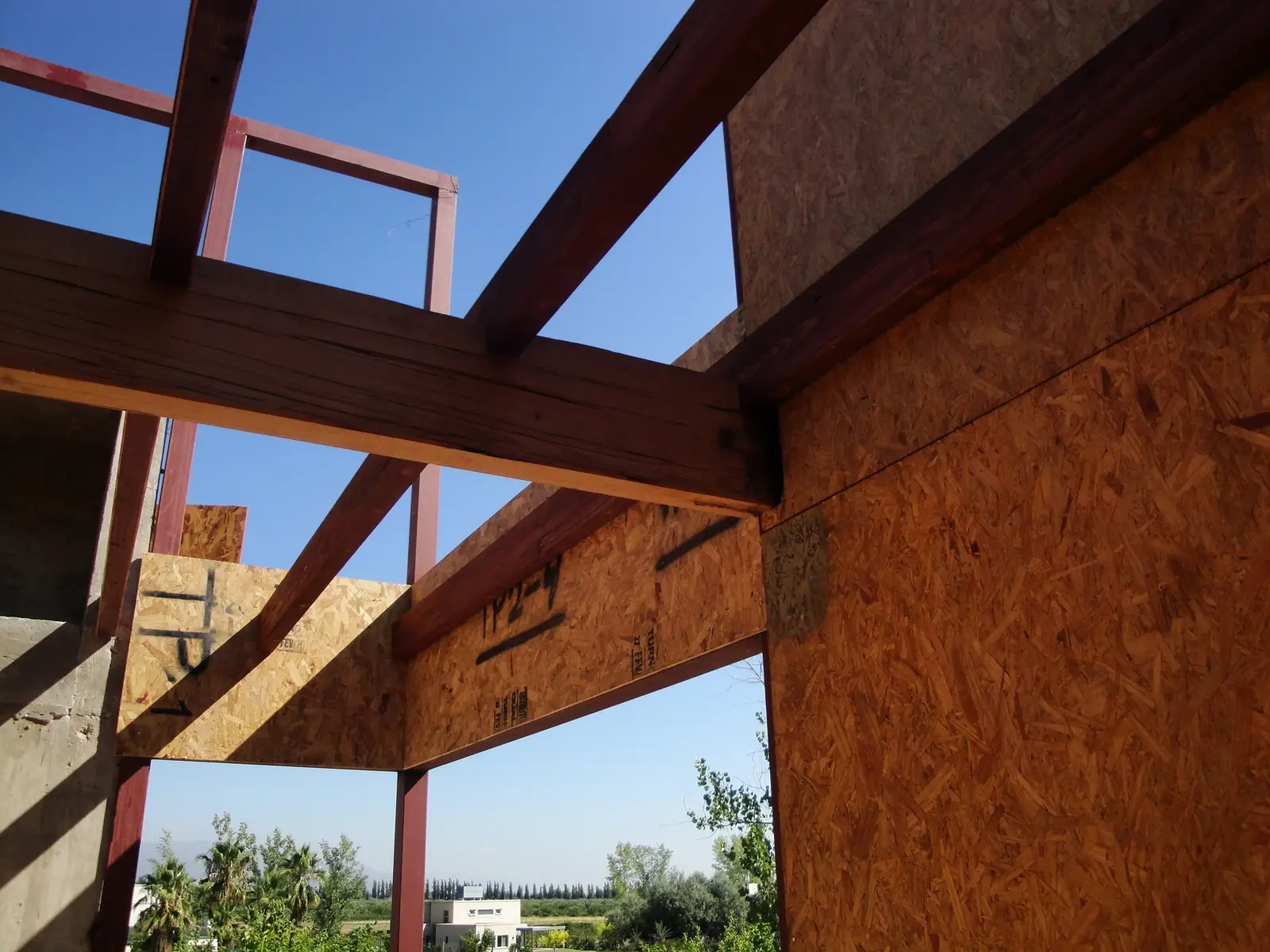 Vigas de madera apoyadas sobre el muro de paneles SIP bajo cielo despejado