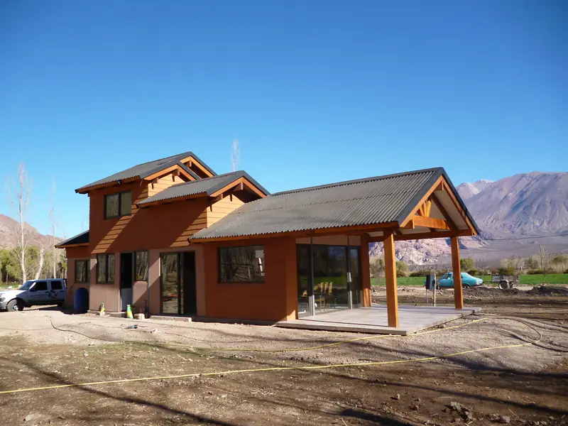 Vista general de la vivienda terminada con techos a dos aguas y galería