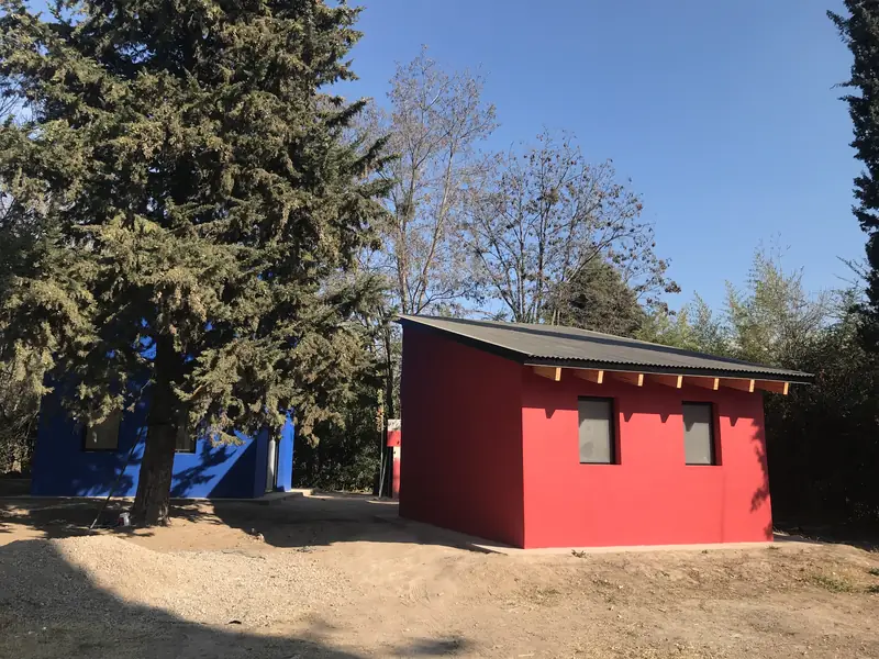 Casita roja de techo inclinado bajo la copa de los pinos