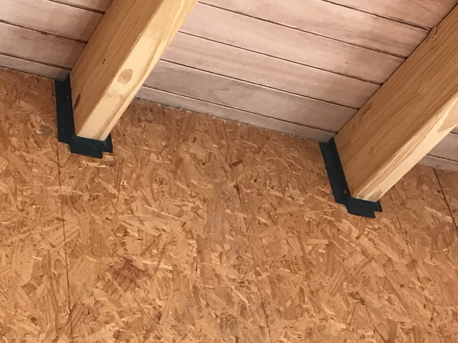 Encuentro de muro de OSB con vigas de madera y ménsulas negras