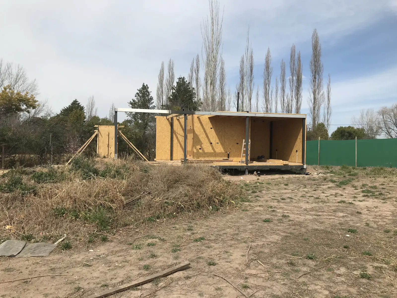 Dos módulos en construcción sobre el terreno arbolado, con los paneles montados