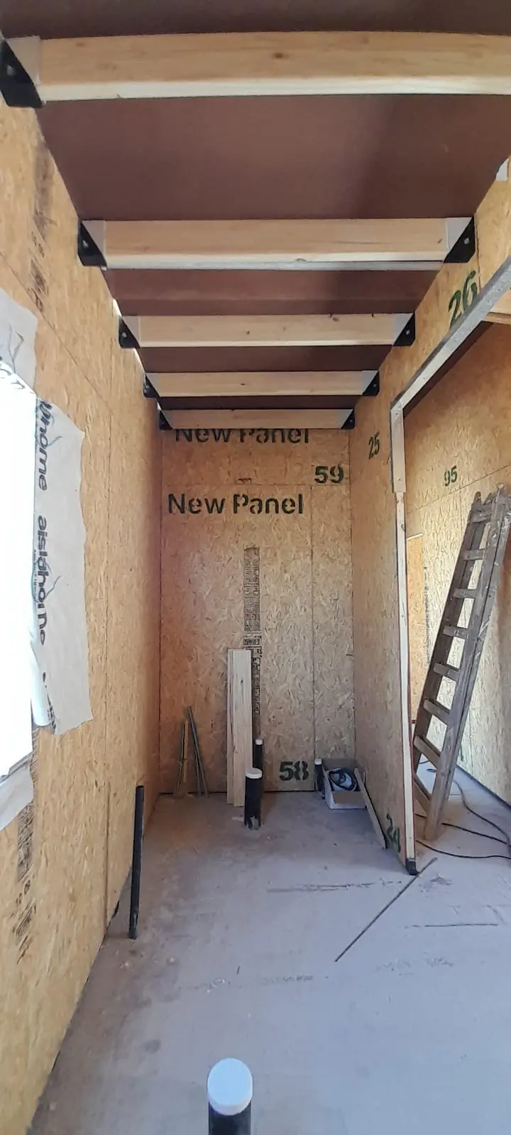 Pasillo interior con paneles New Panel a la vista y vigas de madera