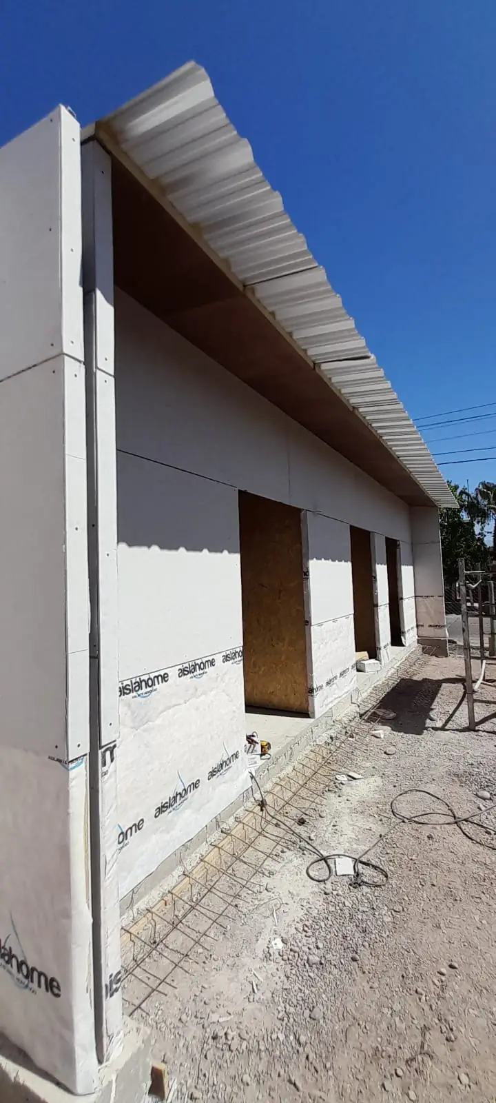 Muro blanco con alero de chapa y galería de vanos hacia el patio