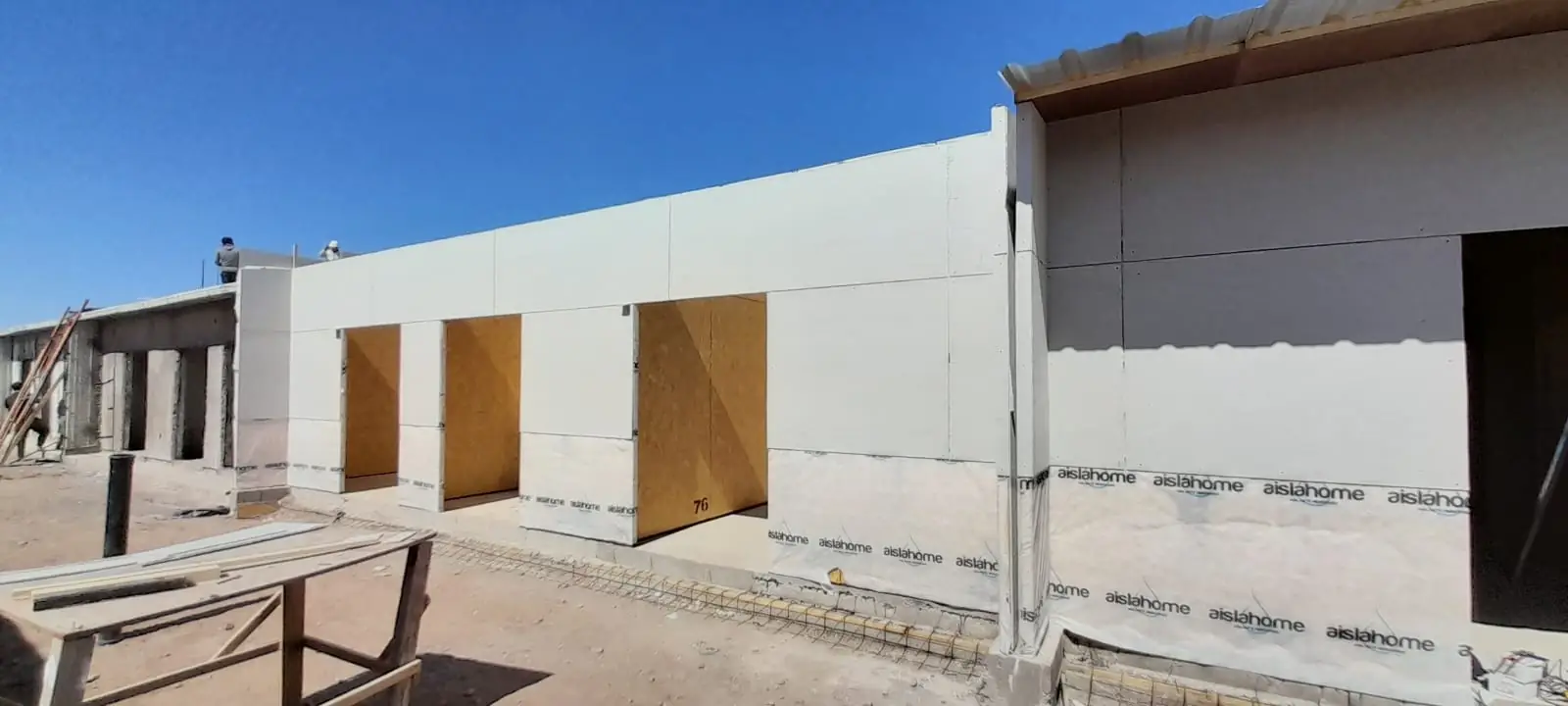 Esquina de vivienda con hilera de aberturas y mesa de trabajo en obra