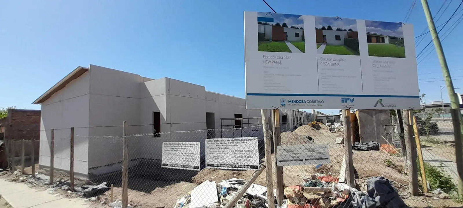 Cartel de obra pública frente a las viviendas de paneles en construcción
