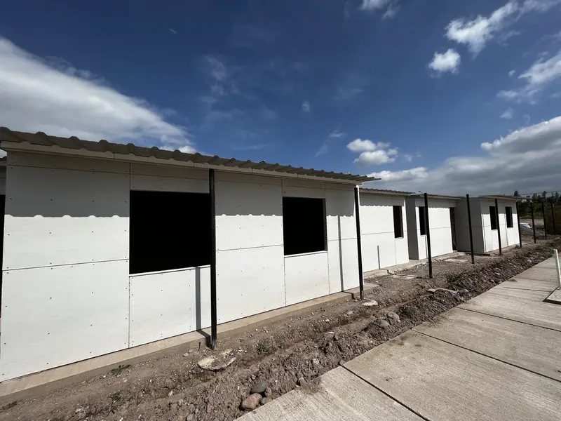 Fila de viviendas blancas alineadas con los vanos de ventana todavía abiertos