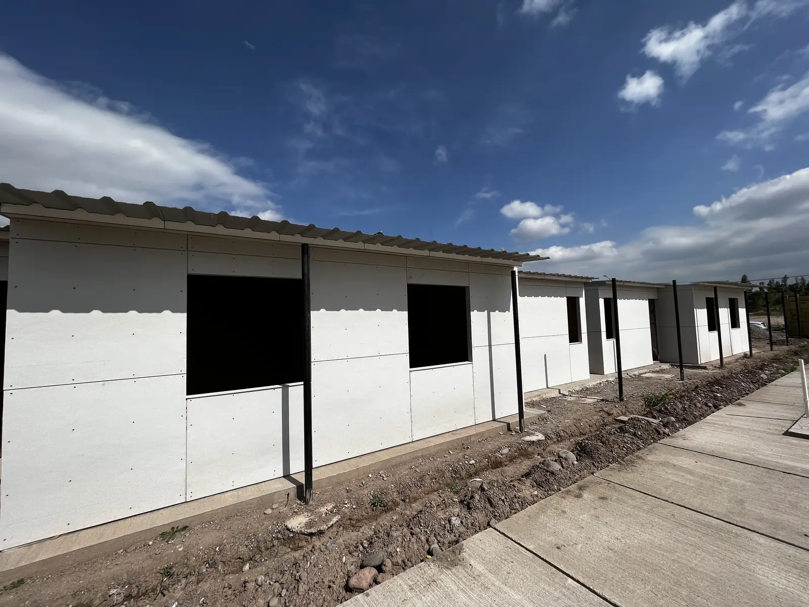 Fila de viviendas blancas alineadas con los vanos de ventana todavía abiertos