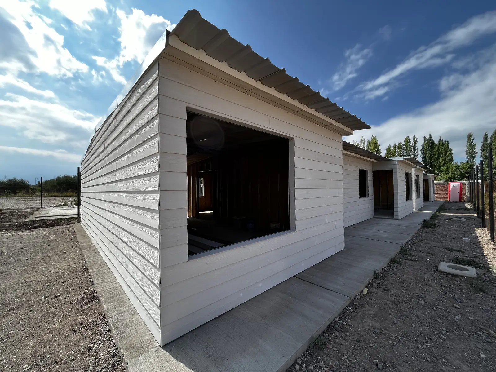 Fachada blanca con gran vano de ventana bajo cielo despejado