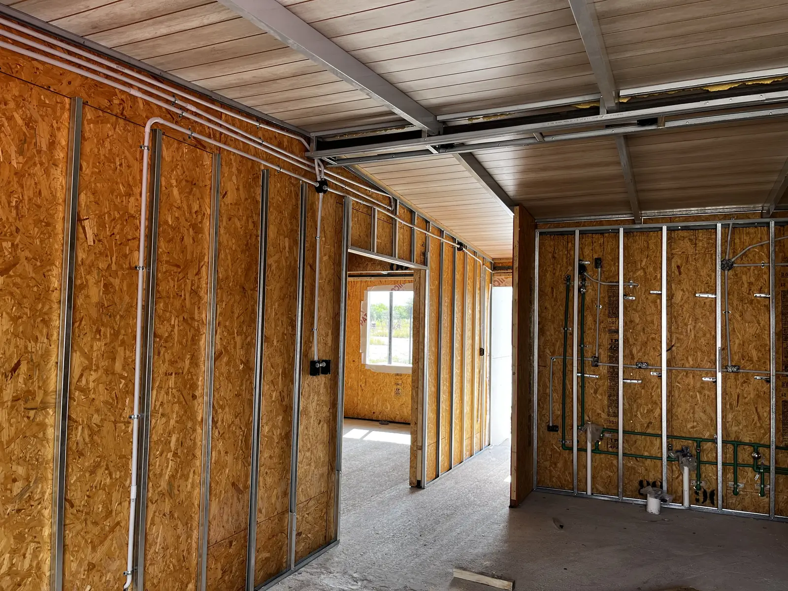 Interior en obra con muros de panel SIP y cielorraso metálico ya colocado