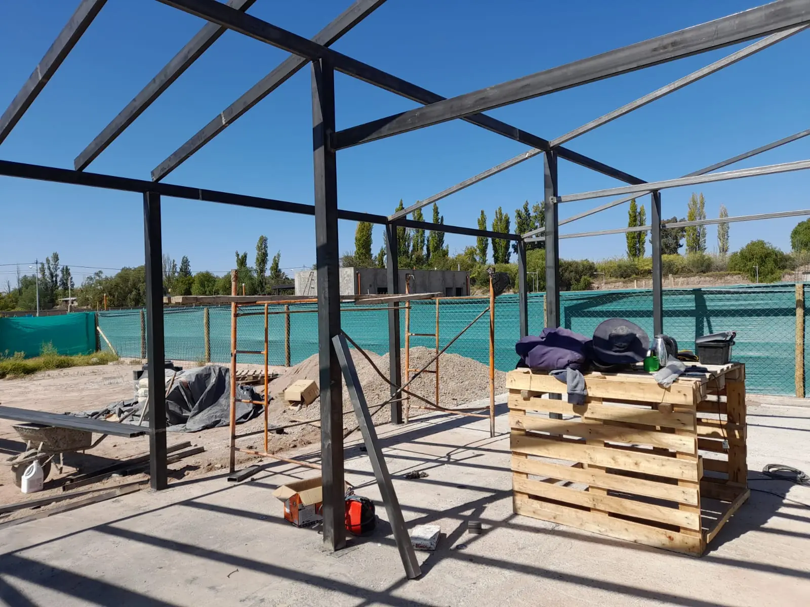 Estructura metálica completa sobre platea de hormigón con pallets de material