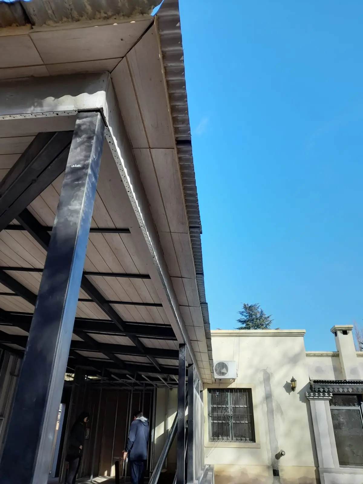 Galería cubierta que recorre el frente de la casa, con una persona caminando