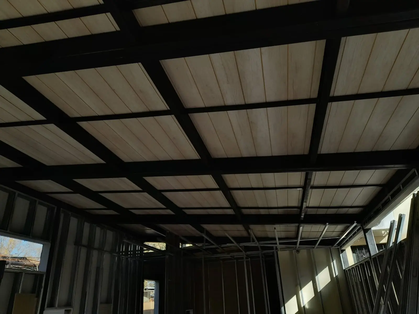 Espacio interior bajo la cubierta con estructura negra y grandes paños vidriados