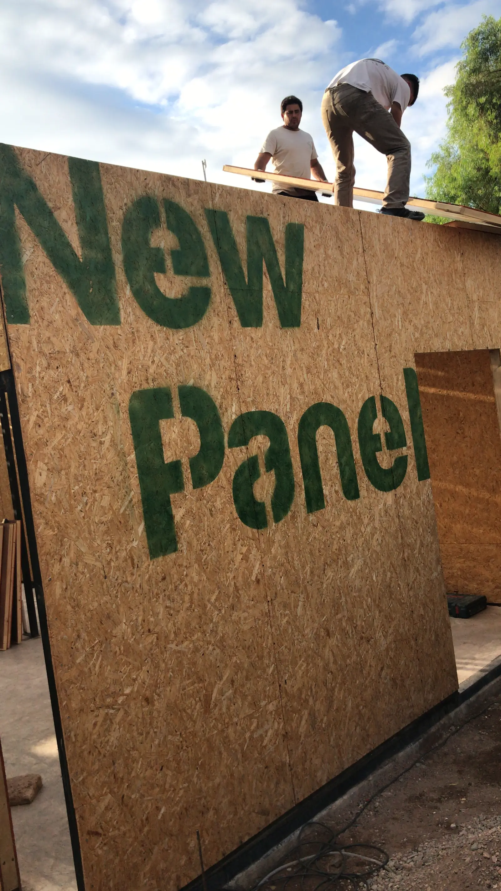 Operarios manipulando un panel SIP con logotipo New Panel a contraluz