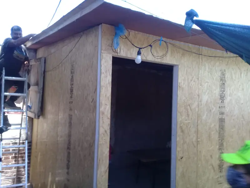 Módulo habitacional de paneles SIP con techo terminado y operario en escalera