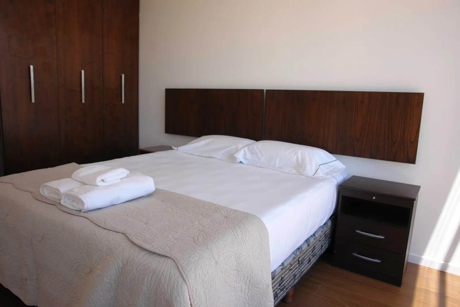 Dormitorio terminado con cama, mesa de luz y placard de madera oscura