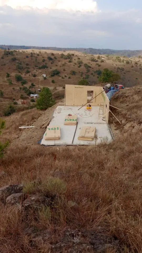 La obra vista desde lejos entre pastizales secos y lomas del entorno
