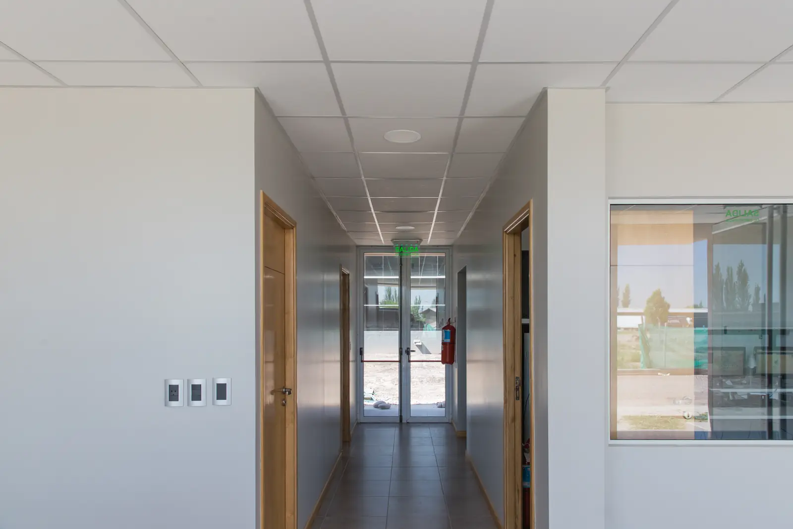 Pasillo interior terminado con cielorraso, puertas de madera y salida al exterior