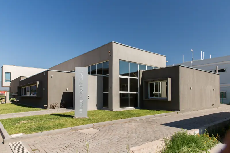 Volumen del edificio de oficinas con frente vidriado y sendero de adoquines