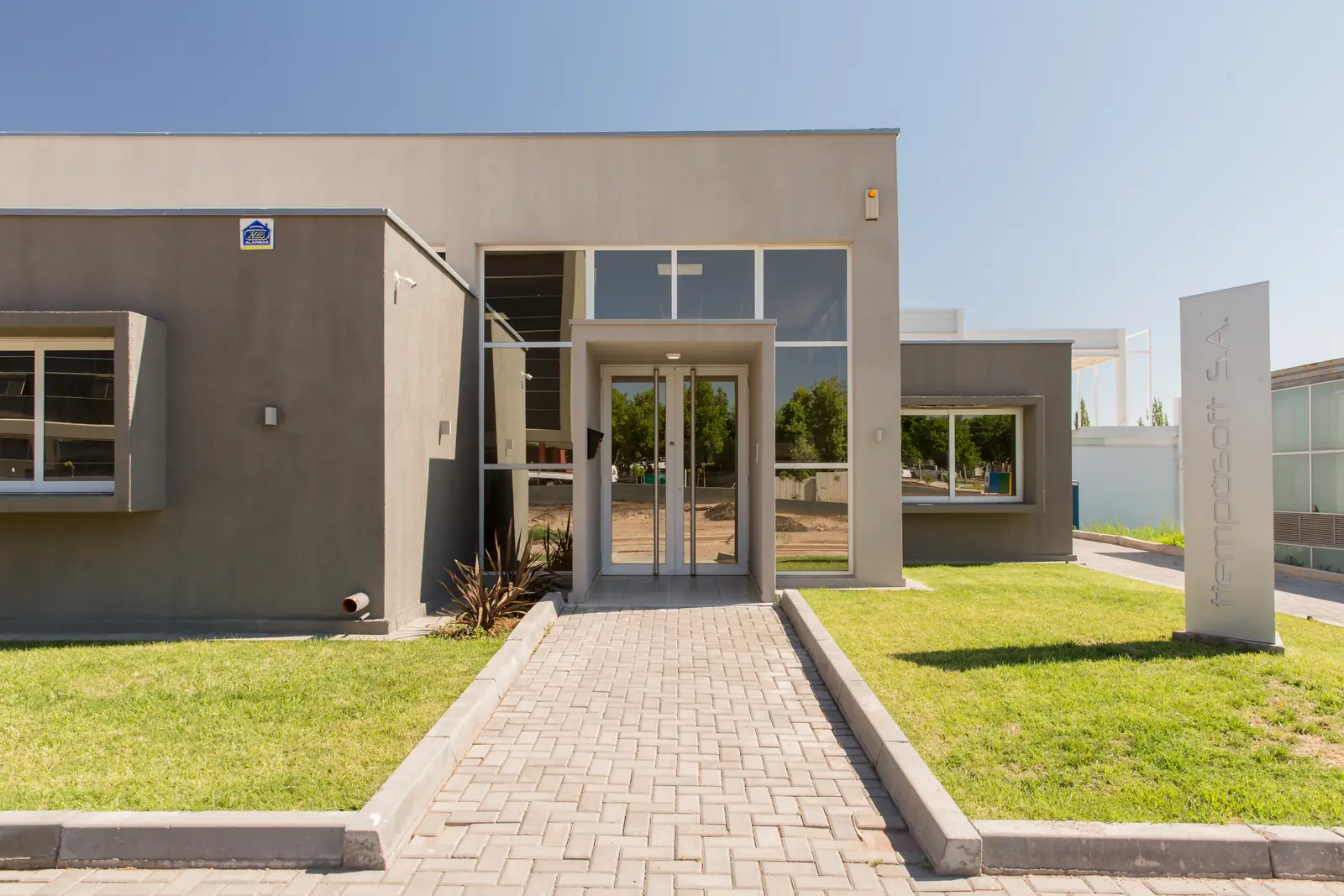 Acceso principal del edificio con camino de adoquines y césped lateral