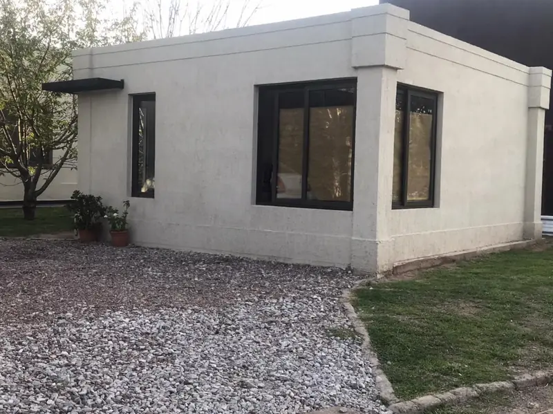 Frente de la vivienda terminada con ventanas negras y césped delantero