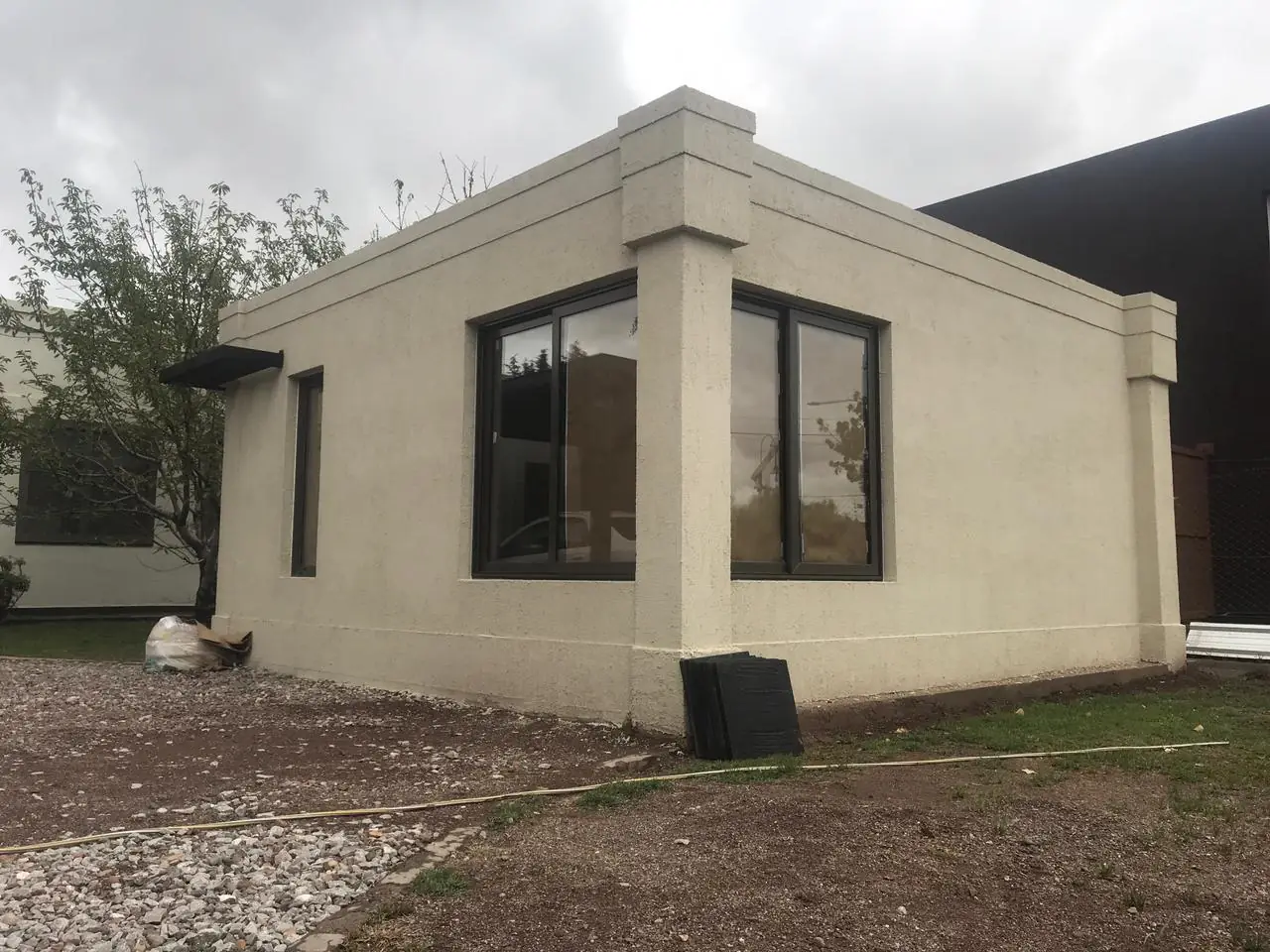 Esquina de la vivienda con ventanal y arboleda del entorno