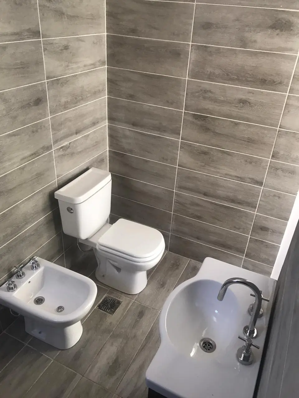 Baño terminado con inodoro, bidet y revestimiento cerámico símil madera