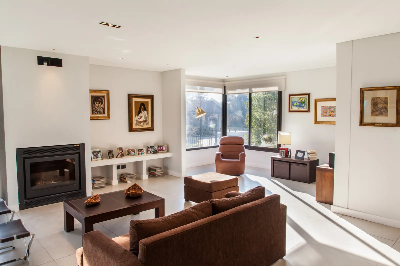 Living integrado con hogar a leña, sillones y ventanal al jardín