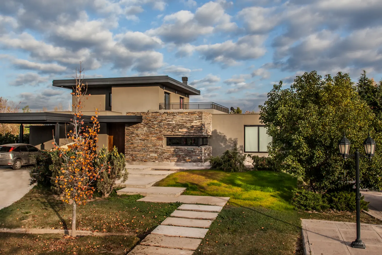 Frente de la vivienda de dos plantas con sendero de losetas y jardín