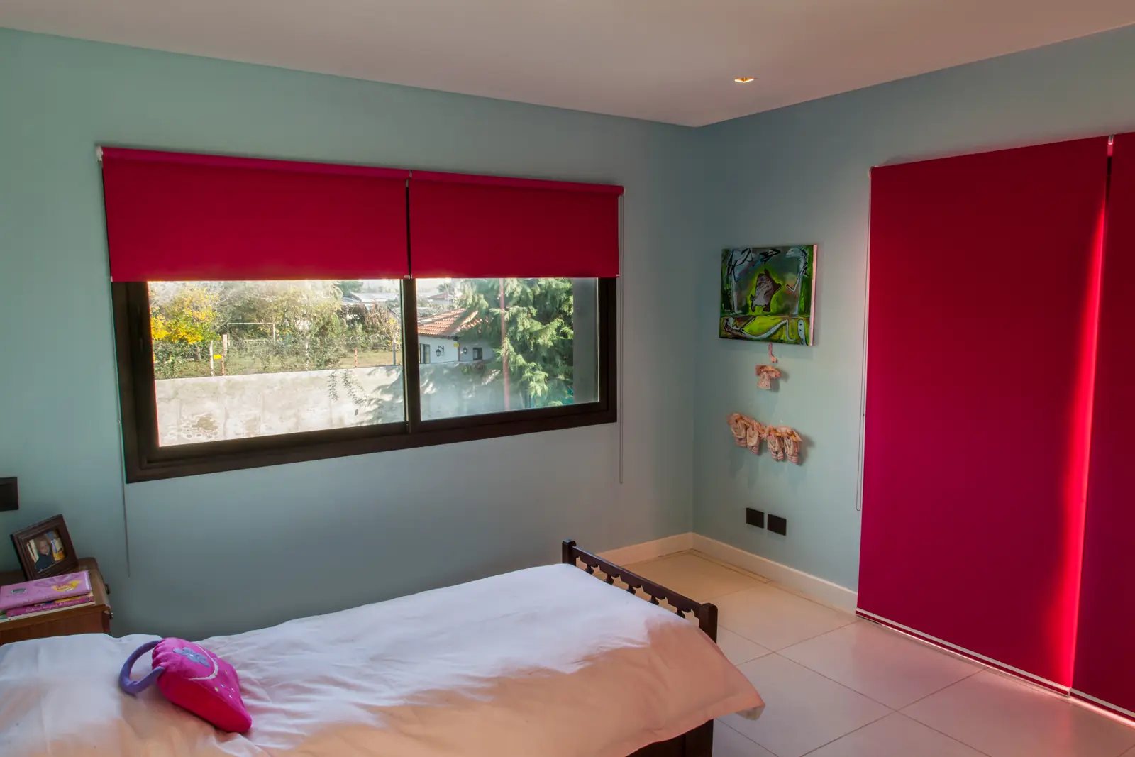 Dormitorio con cortina roller roja, puerta corrediza y paredes claras