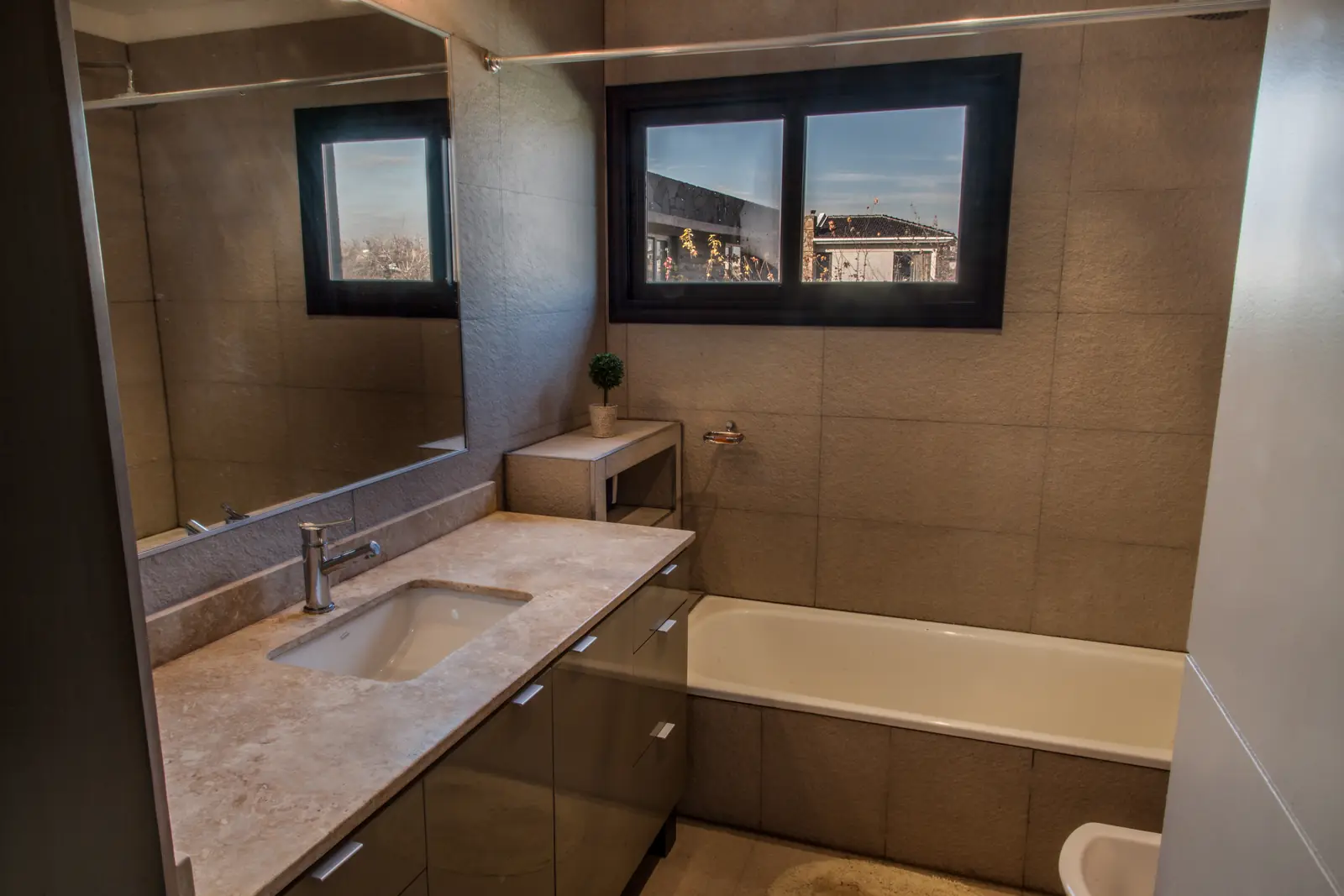 Baño completo con bañera, vanitory de madera y espejo enmarcado