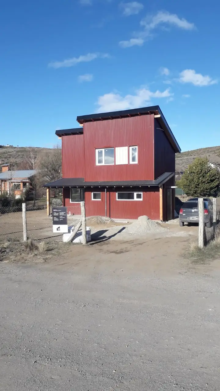 Vivienda terminada de dos plantas con revestimiento bordó y techo a un agua