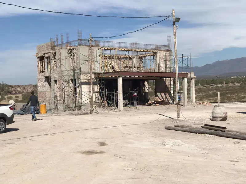 Vista general de la vivienda en obra gruesa con cerros al fondo