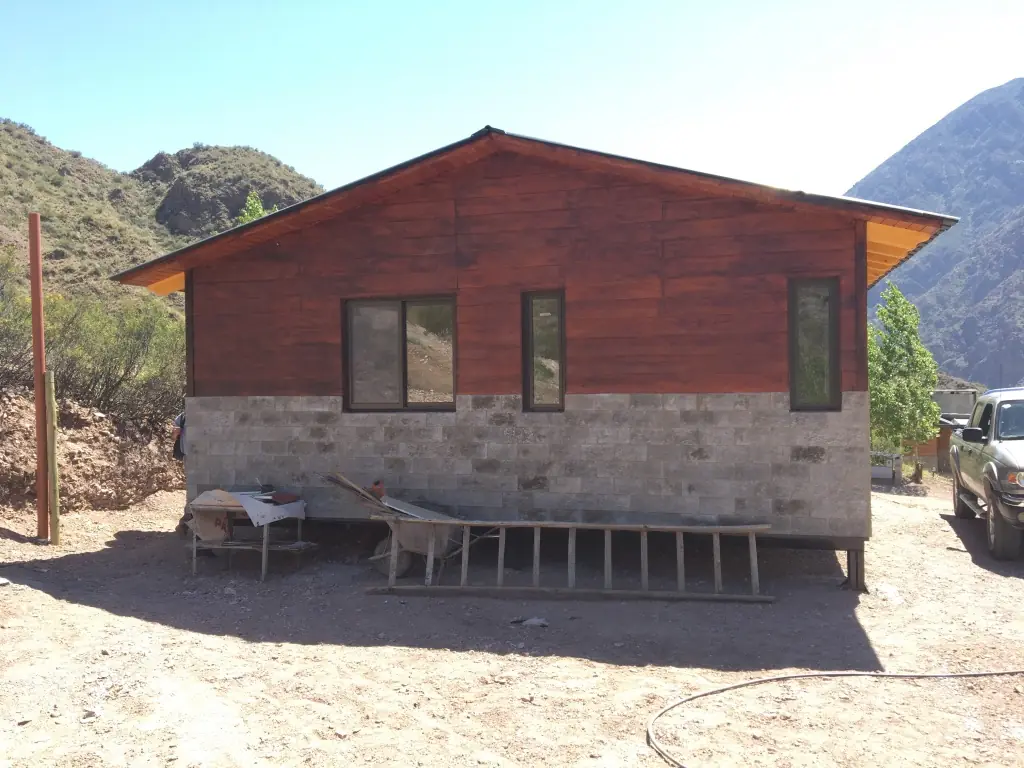Frente de la casa con montañas de fondo y terreno en preparación