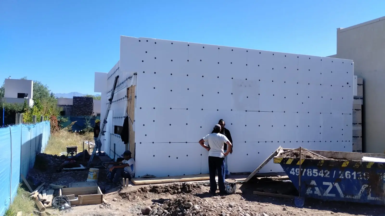 Operarios montando una gran placa de aislación exterior sobre el muro