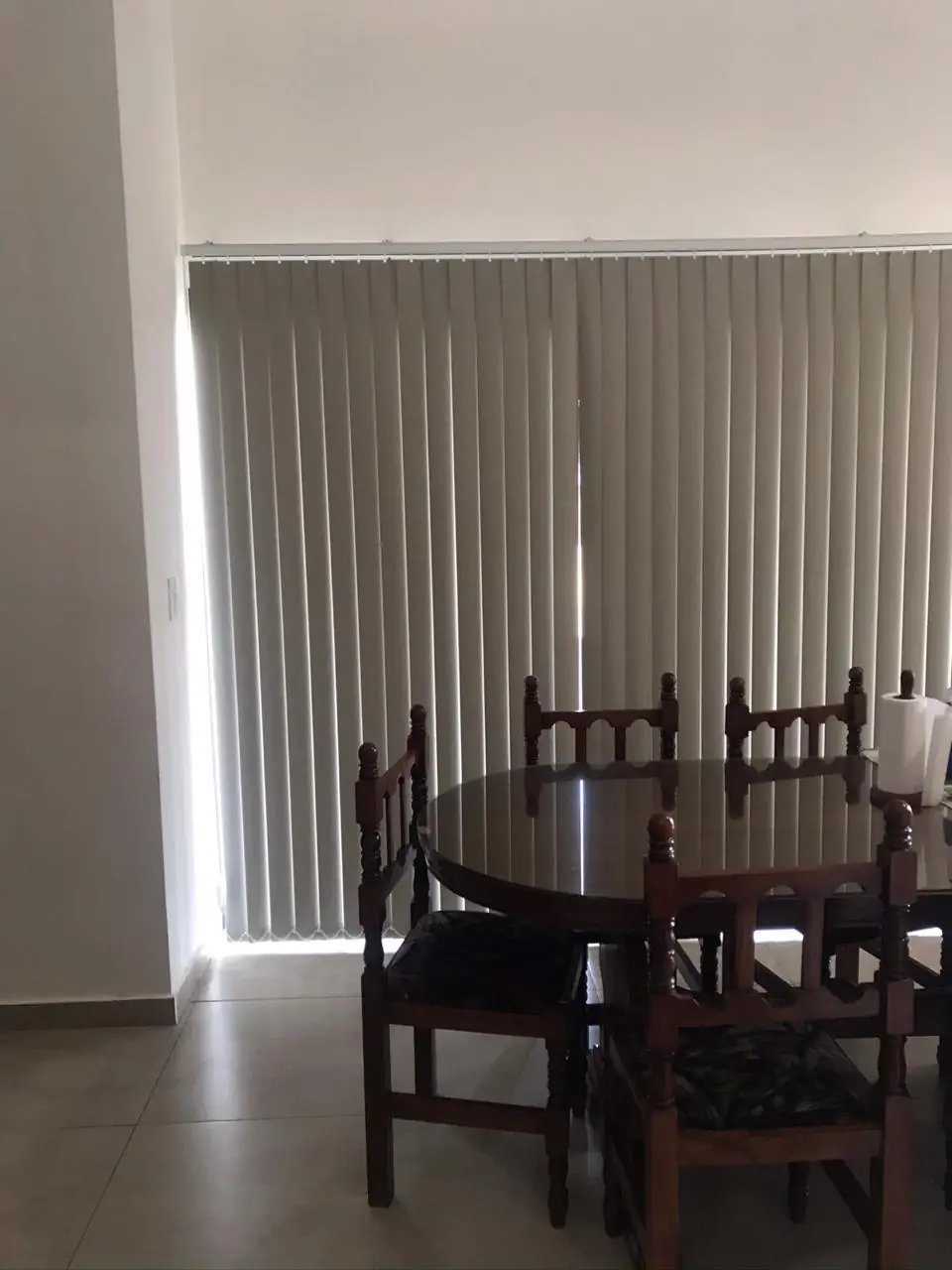 Comedor con mesa y sillas de madera junto a cortinas verticales