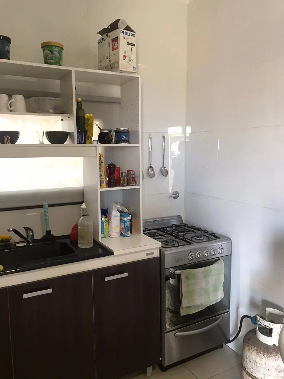 Cocina equipada con bajo mesada oscuro, alacena blanca y cocina a gas