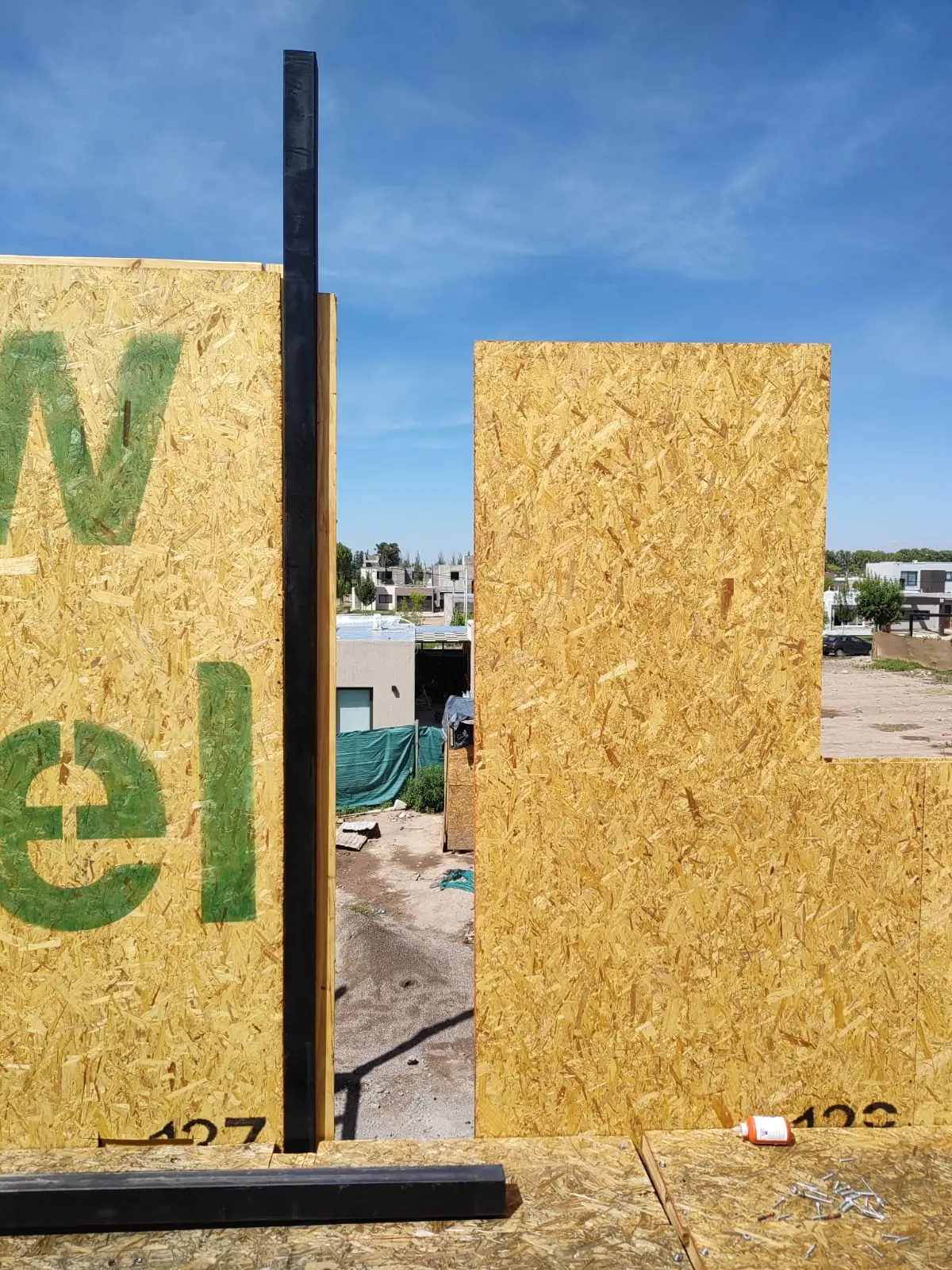 Paneles SIP con logotipo New Panel apoyados en obra bajo cielo despejado