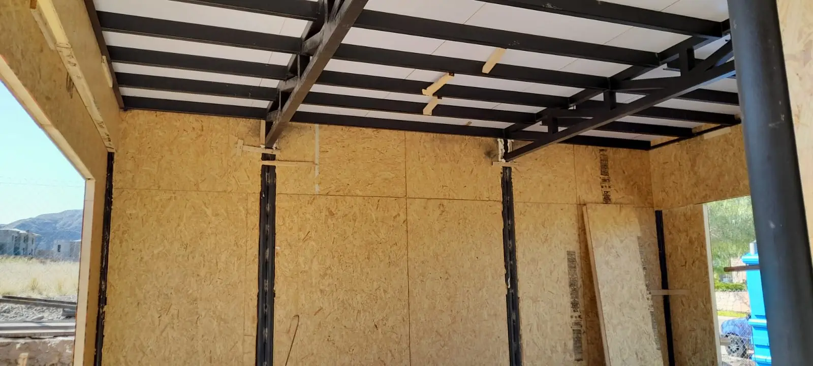 Espacio interior con muros de panel SIP y entramado metálico de cubierta